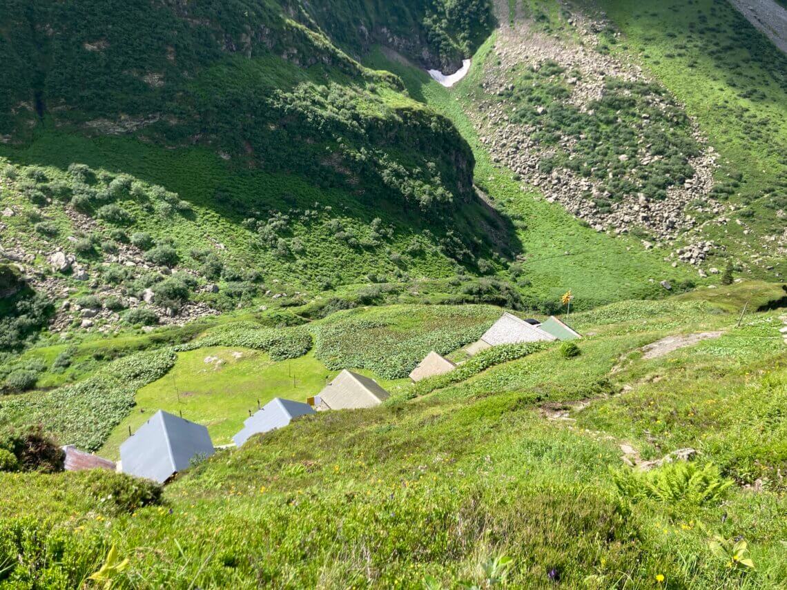 Na een paar uur wandelen zien we wat huisjes en de vlag wapperen van de Cavadirashütte.