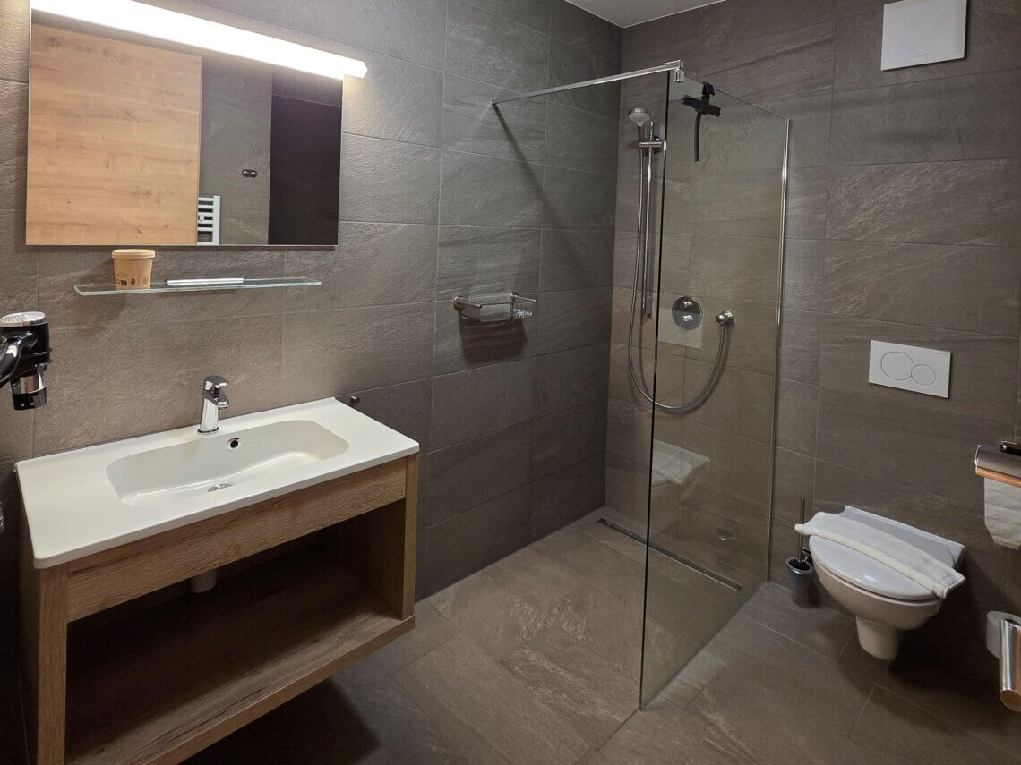 De badkamer met inloopdouche en toilet